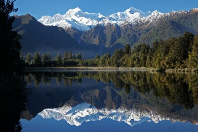 Image of Lake Matheson with a perfect reflection of Aoraki Mt Cook in the background and the Franz and Fox Glaciers