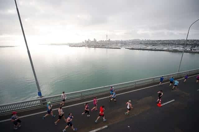 Auckland Marathon runners cross the Auckland Harbour Bridge with the city skyline in the backdrop