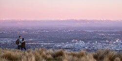 Image taken at dusk of two people looking down from the Port Hills over Christchurch