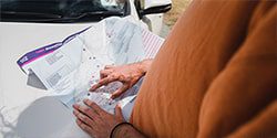 Image of a person studying a map of New Zealand planning a trip - mobile