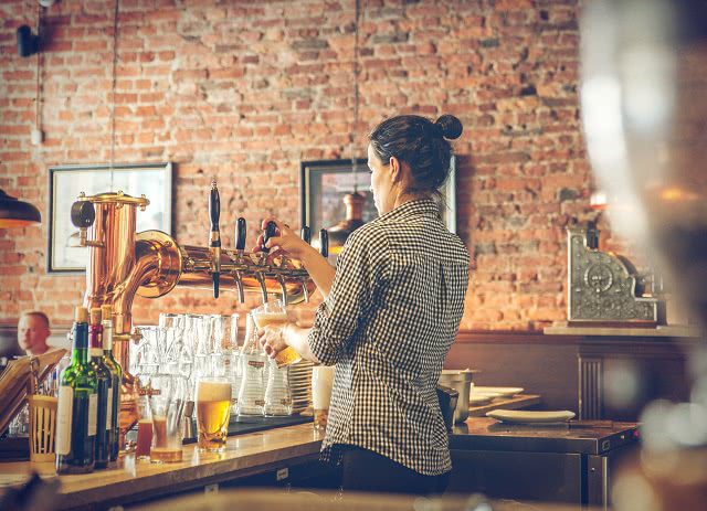 Image of a female bartender pulling a beer