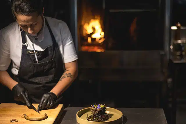 women wearing an apron using a knife and chopping board to prepare food