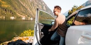 Image of a man stepping out of a vehicle parked beside a lake