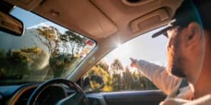 Image of a man in the vehicle pointing towards the sun